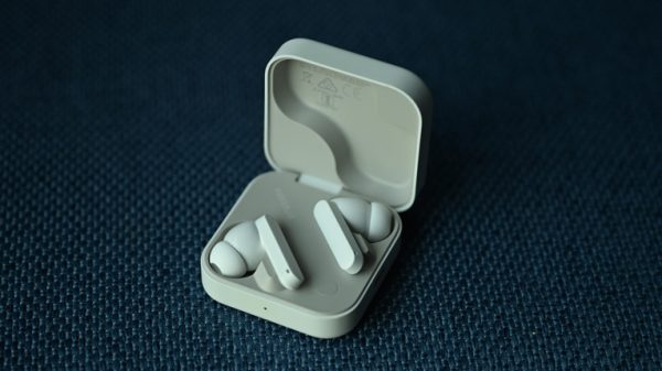 Close-up of CMF Buds 2 Plus earbuds with their square-shaped matte finish case featuring a circular dial on the top left.